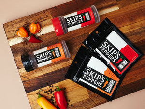 Skip's Peppers blend jars and packets on a cutting board with peppers