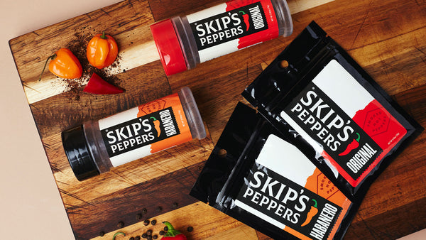 Skip's Peppers blend jars and packets on a cutting board with peppers